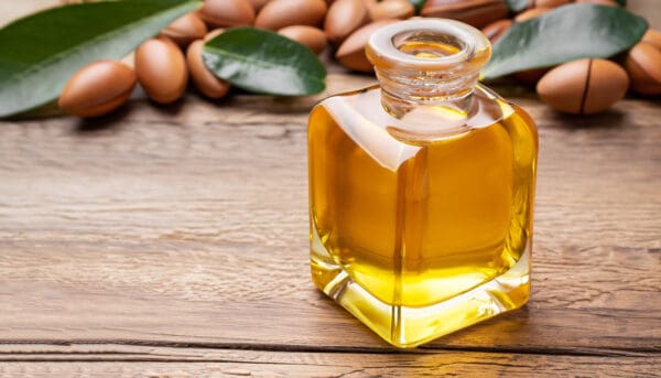 A bottle of argan oil sitting on top of a wooden table.