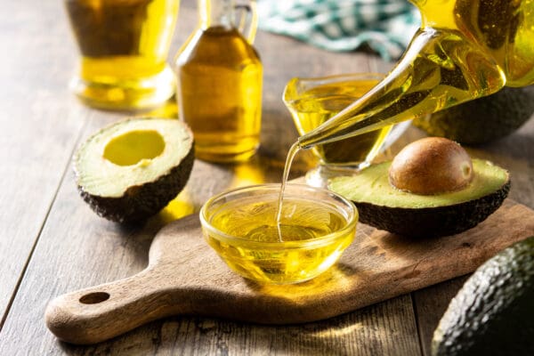 A wooden cutting board with avocado oil and other ingredients.