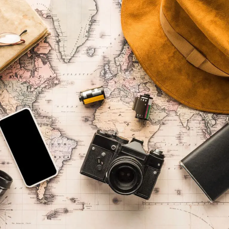 A map with a hat, camera and cell phone on it.