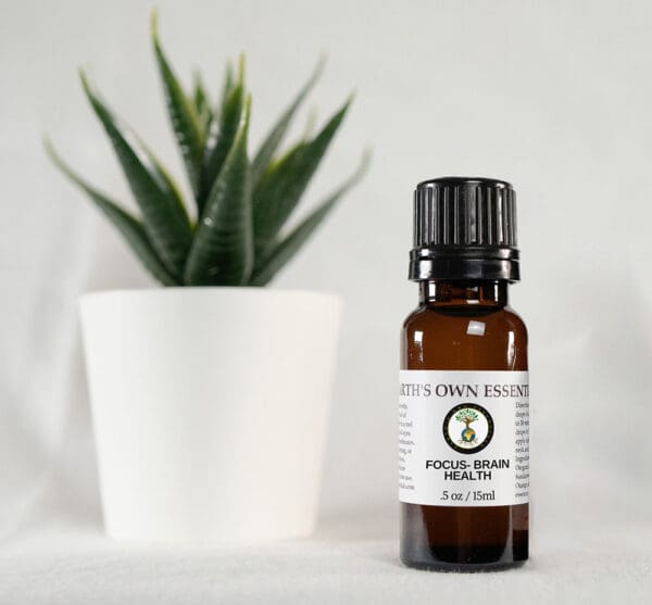 A bottle of essential oil next to a plant.