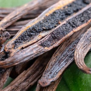 A close up of some vanilla beans on a green surface