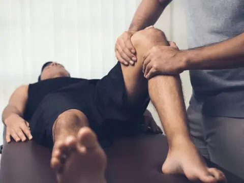 A man is getting his knee examined by an osteopath.