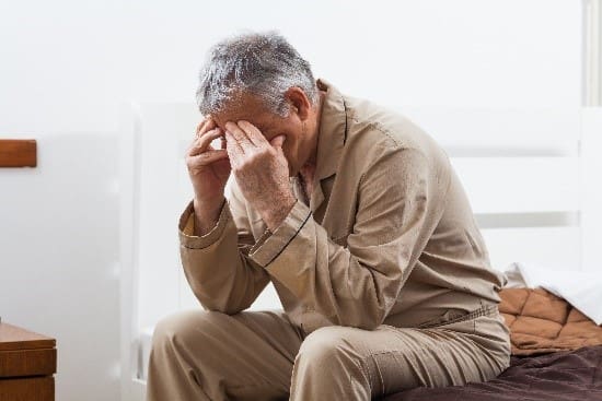 A man sitting down with his hands on the head.