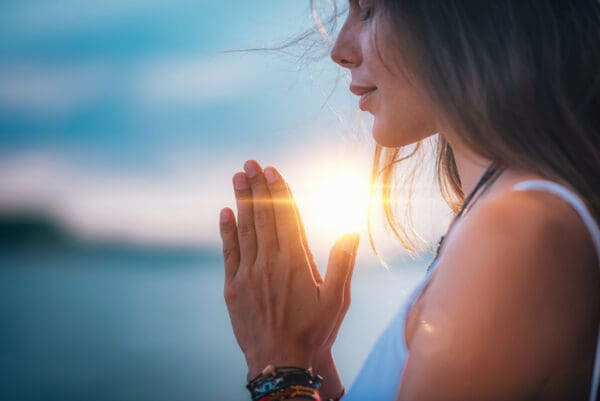 A woman with her hands in prayer.