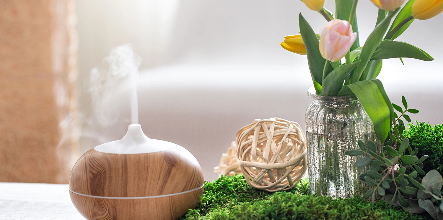 A wooden bowl with flowers in it next to a vase.