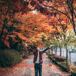 A person standing on the side of a road with their arms outstretched.