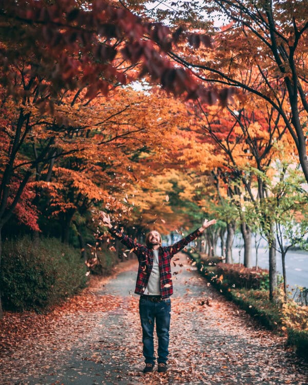 A person standing on the side of a road with their arms outstretched.