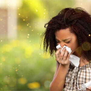 A woman with a cold is blowing her nose.