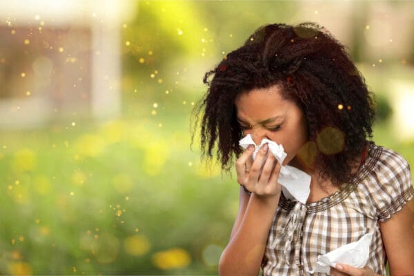 A woman with a cold is blowing her nose.