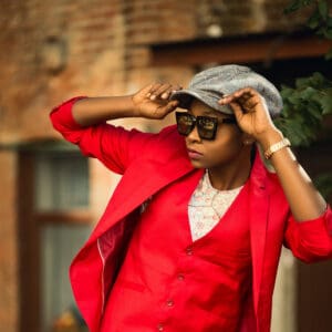 A woman in red jacket and hat holding her hands to the side.