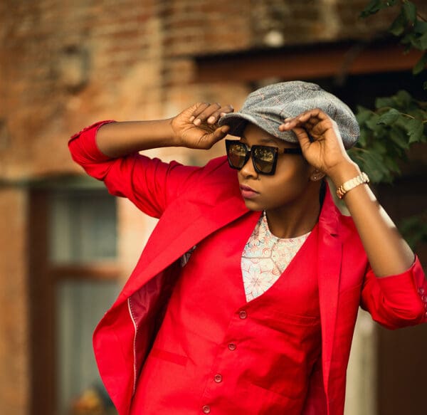 A woman in red jacket and hat holding her hands to the side.