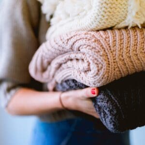 A woman holding two blankets in her hands.