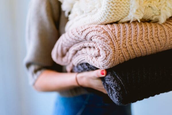 A woman holding two blankets in her hands.