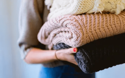 A woman holding some folded sweaters in her hands