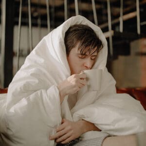 A person wrapped in blankets and holding something