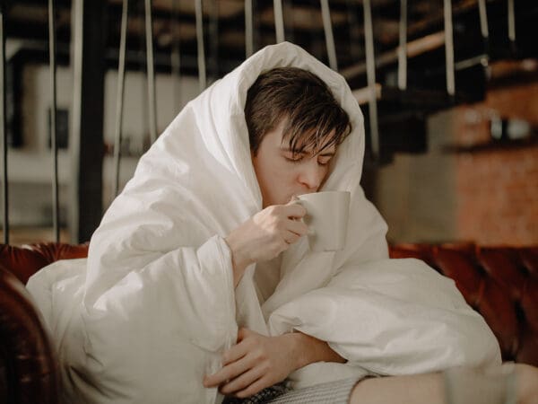 A person wrapped in blankets and holding something