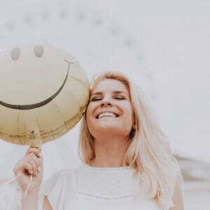 A woman holding onto a balloon with a smile on it