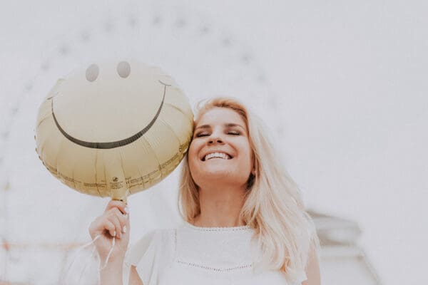 A woman holding onto a balloon with a smile on it