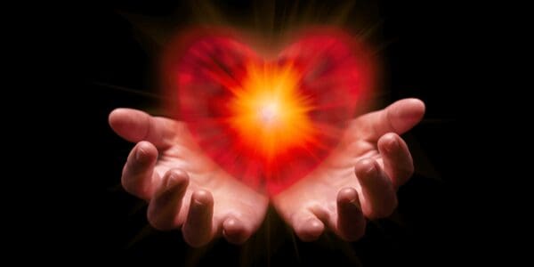 A heart shaped light in the middle of two hands.