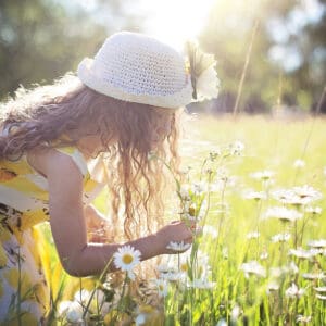 A girl in the grass picking flowers