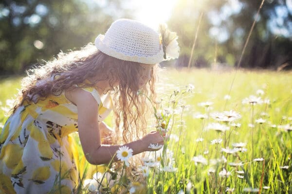 A girl in the grass picking flowers