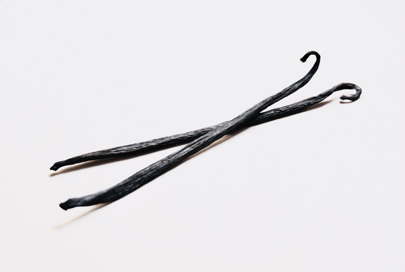 A pair of black hair pins on top of a white surface.