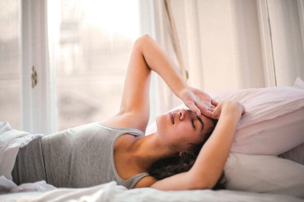 A woman laying in bed with her head on the pillow.