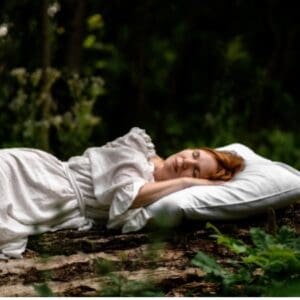 A woman laying on the ground in a forest.