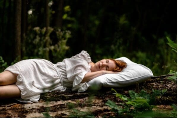 A woman laying on the ground in a forest.