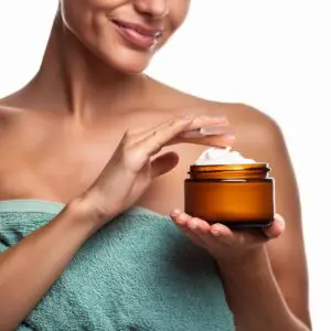 A woman is holding a jar of cream