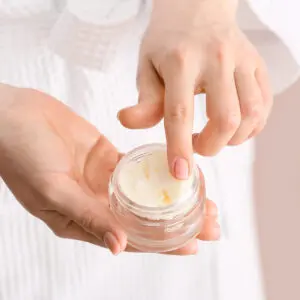 A person holding onto a jar of cream