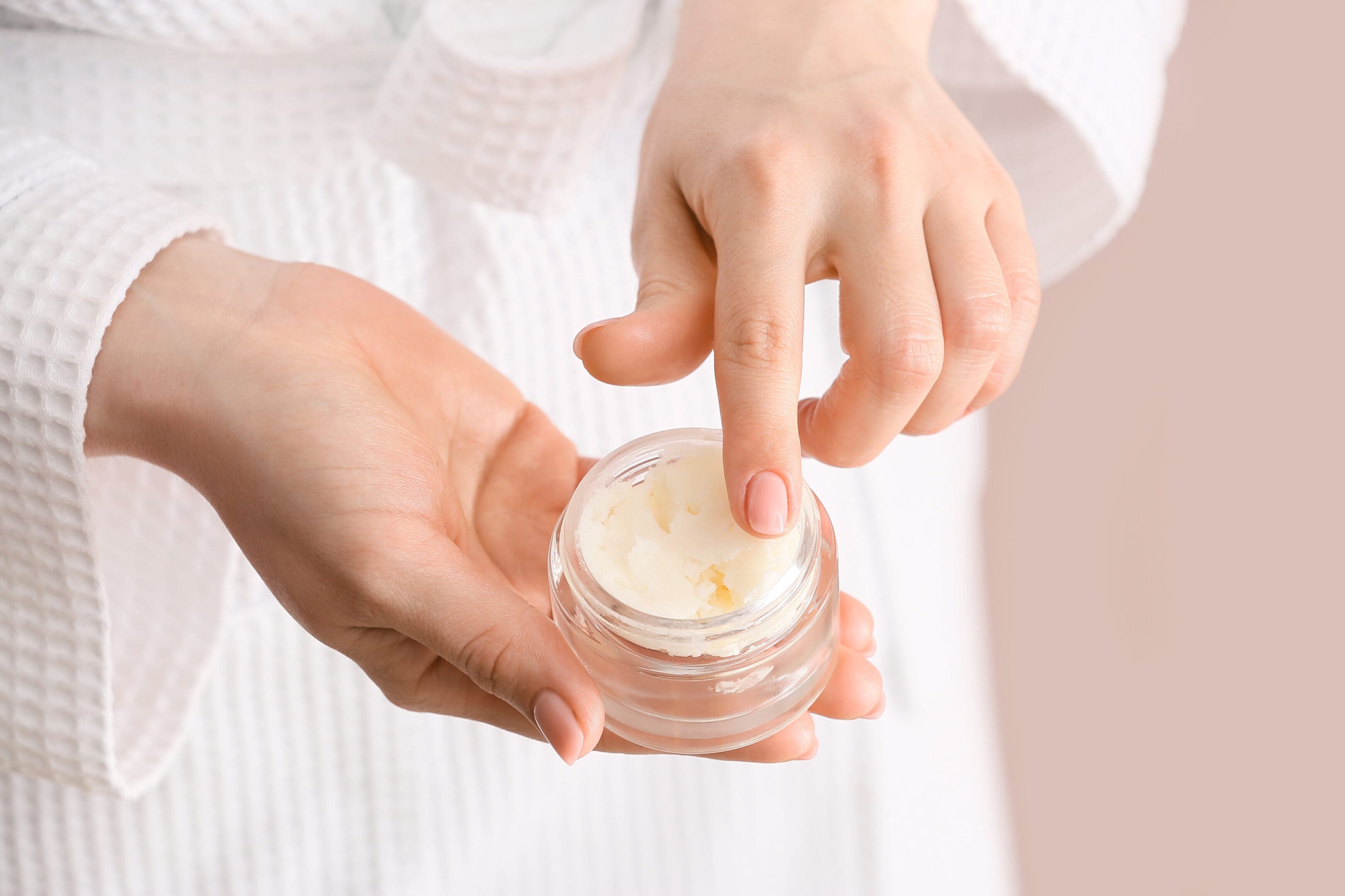 A person holding onto a jar of cream