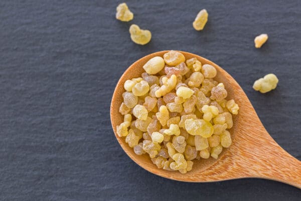 A wooden spoon filled with yellow food on top of a table.