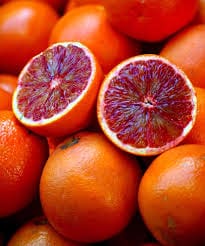 A pile of blood oranges sitting on top of each other.