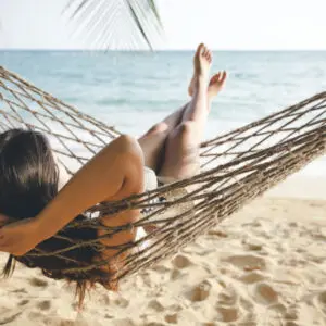 A woman laying in a hammock on the beach.