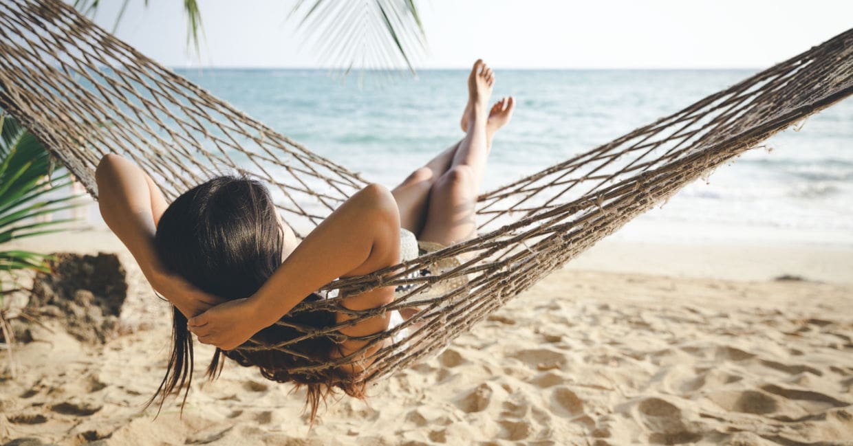 A woman laying in a hammock on the beach.